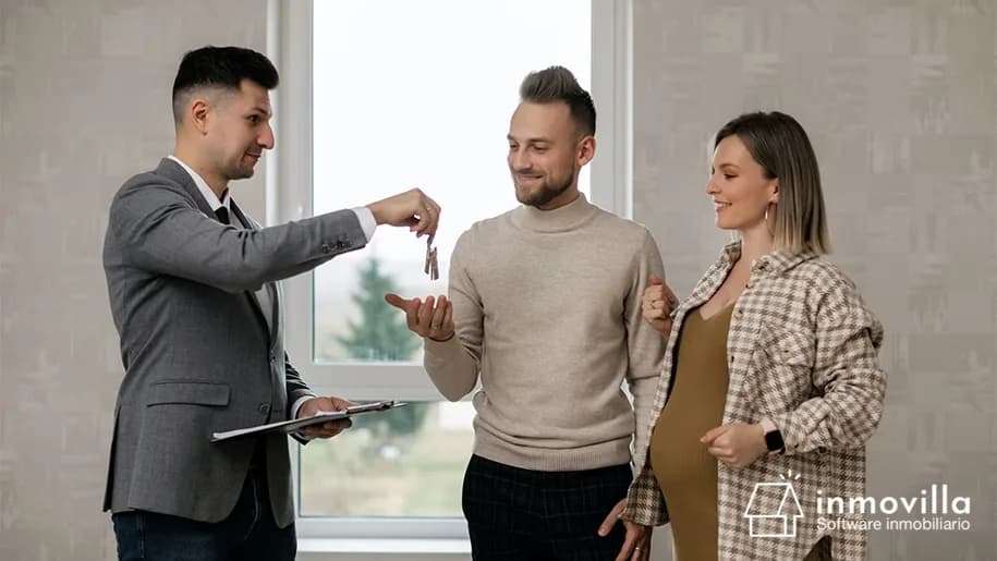 Asesor inmobiliario dando las llaves a pareja de clientes.