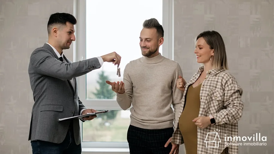 Asesor inmobiliario dando las llaves a pareja de clientes.